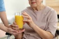 Nurse giving glass of juice to elderly woman, closeup. Assisting senior people Royalty Free Stock Photo