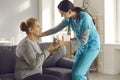 Nurse giving glass of water to senior woman at home, clinic or assisted living facility