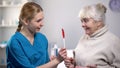 Nurse giving medical pills and lollipop to old woman, taking care about patient Royalty Free Stock Photo