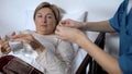 Nurse giving old female patient medicaments and water glass, hospital treatment