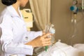 Nurse giving patient water using glass syringe to irrigate nasogastric tube in hospital