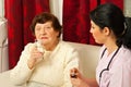 Nurse giving pills and water to senior