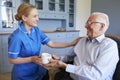 Nurse Giving Senior Man Cup Of Tea On Home Visit Royalty Free Stock Photo