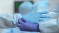 Nurse helping doctor to put medical gloves before operation, hospital sterility