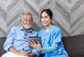 Nurse helping patient for using tablet. Caretaker and senior man using tablet PC at nursing home Royalty Free Stock Photo