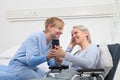 Nurse helps with cell phone to contact the elderly lady`s family in the wheelchair near bed in hospital room, concept of Royalty Free Stock Photo