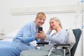 Nurse helps with cell phone to contact the elderly lady`s family in the wheelchair near bed in hospital room, concept of Royalty Free Stock Photo