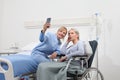 Nurse helps with cell phone to contact the elderly lady`s family in the wheelchair near bed in hospital room, concept of Royalty Free Stock Photo