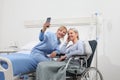 Nurse helps with cell phone to contact the elderly lady`s family in the wheelchair near bed in hospital room, concept of Royalty Free Stock Photo