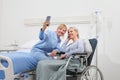 Nurse helps with cell phone to contact the elderly lady`s family in the wheelchair near bed in hospital room, concept of Royalty Free Stock Photo