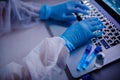 Nurse hold blood test tube in white hazmat protective suit in laboratory computer. Concept study antidote against Royalty Free Stock Photo