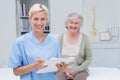 Nurse holding clipboard while female patient sitting in clinic Royalty Free Stock Photo