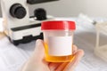 Nurse holding container with urine sample for analysis at table, closeup Royalty Free Stock Photo