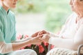 Nurse holding hands of disabled elderly woman