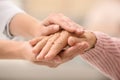 Nurse holding hands of elderly woman against blurred background. Assisting senior generation