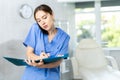 Nurse holding mobile phone between ear and shoulder talking and writing notes to clipboard Royalty Free Stock Photo