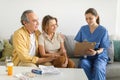 Nurse during home visit with senior couple, doctor holding clipboard in conversation with old man and woman Royalty Free Stock Photo