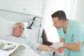 Nurse inserting needle into arm senior male hospital patient