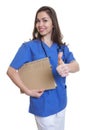 Nurse with long dark hair and file showing thumb up Royalty Free Stock Photo