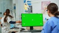 Nurse looking at green screen display while doctor examining patient