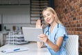 Nurse looking at tablet, make video call, waving hand in camera