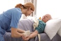 Nurse making injection to elderly man on bed. Medical assistance