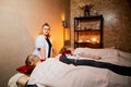 Nurse making a Spa mud mask on a girl`s face in a salon or room with a couch, white towels and a beautiful light