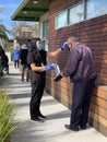 Nurse in mask checks a senior man temperature outside of vaccination clinic
