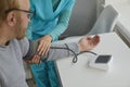 Nurse measure blood pressure of a sick senior mature male patient in clinic closeup. Royalty Free Stock Photo