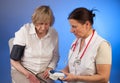 Nurse measures bloodpressure of eldely woman Royalty Free Stock Photo