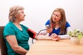 Nurse measures senior the blood pressure