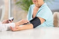 Nurse measuring blood pressure of elderly woman indoors. Assisting senior generation Royalty Free Stock Photo