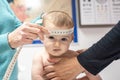 Nurse measuring the cranial perimeter of a baby in a clinic with a tape measure