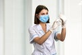 Nurse in medical mask looking at syringe. Royalty Free Stock Photo