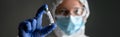 Nurse in medical PPE suit holds bottle with vaccine for COVID-19 cure