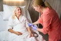 Nurse in orange uniform puts a drip on beautiful woman Royalty Free Stock Photo