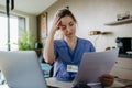 Nurse paying bills online, sitting in living room, working on notebook. Doctor in scrubs dealing with work issues from Royalty Free Stock Photo