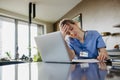 Nurse paying bills online, sitting in living room, working on notebook. Doctor in scrubs dealing with work issues from Royalty Free Stock Photo