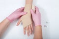 Nurse with pink gloves wrapping young girls hand with ace bandage