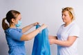 The nurse prepares the patient for hospitalization. Wears a disposable blue gown on a white background.