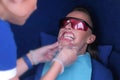 Nurse Preparing woman to LED whitening teeth installs dental retractor.