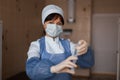Nurse in a protective mask in medical clothes is standing and looking at the camera in the arm, holding a syringe in her hand. Royalty Free Stock Photo