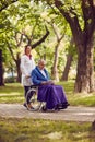 Nurse pushing elderly man in wheelchair while reading book Royalty Free Stock Photo