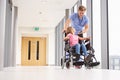 Nurse Pushing Girl In Wheelchair Along Corridor Royalty Free Stock Photo