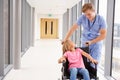 Nurse Pushing Girl In Wheelchair Along Corridor Royalty Free Stock Photo