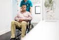 Nurse pushing mature patient wheelchair in hospital
