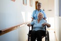 Nurse pushing patient sitting in wheelchair at nursing home Royalty Free Stock Photo