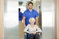 Nurse pushing senior patient in wheelchair along corridor Royalty Free Stock Photo