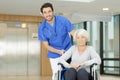 nurse pushing senior patient in wheelchair along corridor Royalty Free Stock Photo