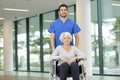 nurse pushing senior patient in wheelchair along corridor Royalty Free Stock Photo